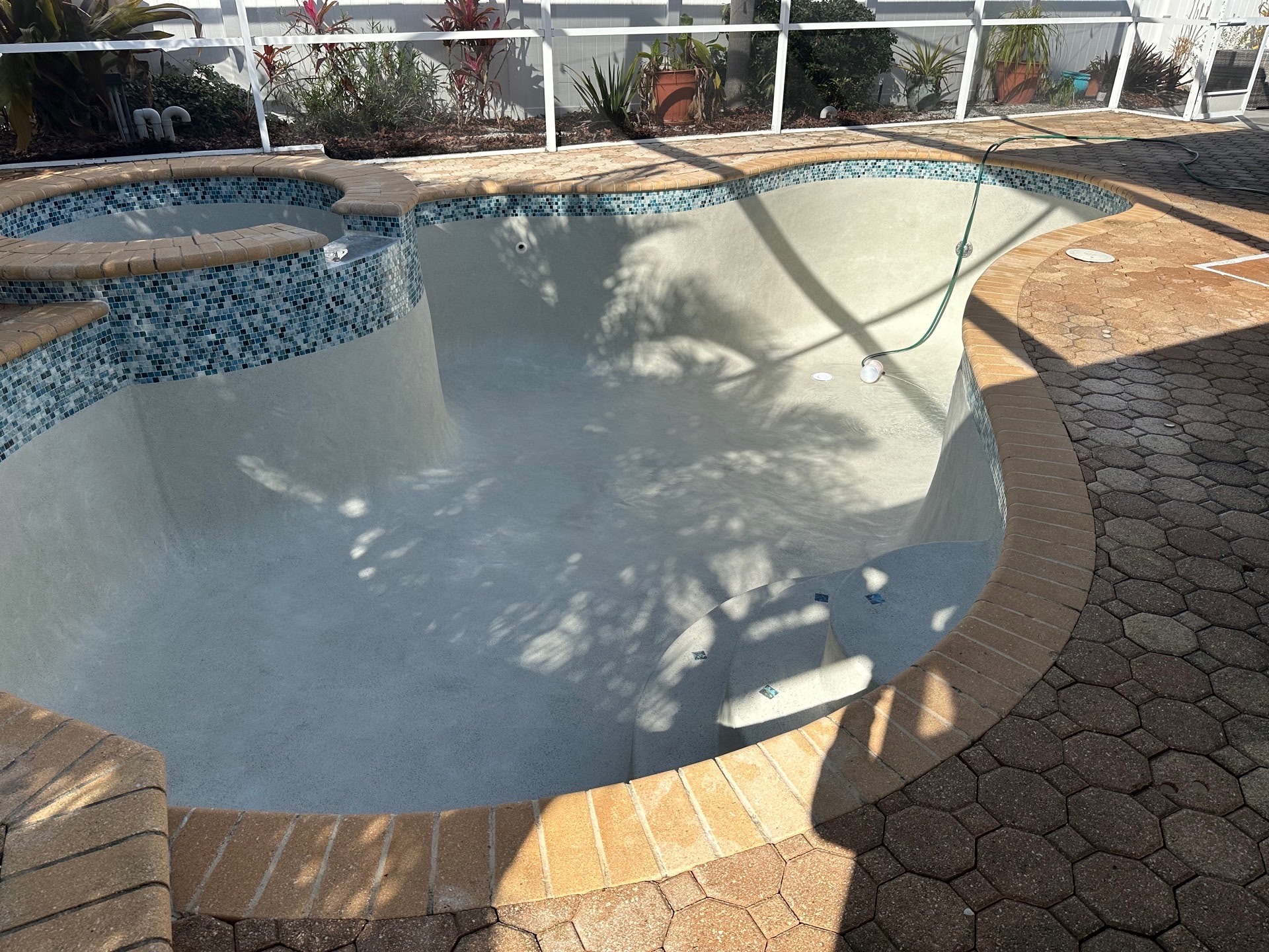 Freshly resurfaced pool and spa with glass tile and brick coping